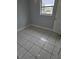 A simple bedroom with gray walls, tile flooring, and a window allowing natural light at 58 Lincoln St, Frostproof, FL 33843