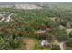 Aerial view showing the property boundaries surrounded by lush trees, other homes, and a pond at 6340 Nelms E Rd, Lakeland, FL 33811