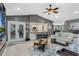 Open-concept living room with modern gray walls, ceiling fan, open kitchen view, and access to the outdoor patio at 6340 Nelms E Rd, Lakeland, FL 33811