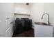 Modern laundry room with washer, dryer, sink, white cabinets and dark wood floors at 8374 Bowden Way, Windermere, FL 34786