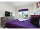 Bedroom features a window, dresser, television, and a plush bed with purple bedding at 9075 Dogleg Dr, Davenport, FL 33896