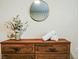 Close-up of a wood dresser with a round mirror, white flowers, and rolled white towels at 9075 Dogleg Dr, Davenport, FL 33896