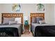 A cozy bedroom featuring two twin beds with stylish wooden headboards and decorative abstract art at 9075 Dogleg Dr, Davenport, FL 33896
