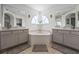 Bright bathroom featuring dual sinks, mirrors, a soaking tub, and a large window providing natural light at 107 Troon Cir, Davenport, FL 33897