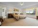 Bright bedroom featuring neutral carpeting, a ceiling fan, and a large window with lovely draperies at 107 Troon Cir, Davenport, FL 33897