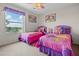 Bedroom featuring two beds with pink and purple bedding, decorative wall art, and a window at 107 Troon Cir, Davenport, FL 33897
