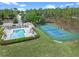 An aerial view of a community pool, tennis court, and clubhouse, with green landscaping and mature trees at 107 Troon Cir, Davenport, FL 33897