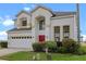 Charming two-story home featuring a red door, neutral stucco exterior, and an attached two car garage at 107 Troon Cir, Davenport, FL 33897