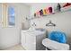 Bright laundry room with a washer, dryer, shelving for supplies, and a window that provides natural light at 107 Troon Cir, Davenport, FL 33897