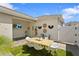 Outdoor patio features a dining set, string lights, tropical decor, and white fence, ideal for outdoor gatherings at 11473 Listening Dr, Orlando, FL 32832