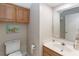 Cozy bathroom featuring a toilet, vanity with sink, mirror, and wood cabinets for storage at 1730 King Henry Dr, Kissimmee, FL 34744