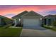 Attractive one-story home with a two-car garage, lush lawn, and inviting facade under a colorful sky at 1774 Walnut Creek Dr, Kissimmee, FL 34744