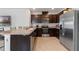 Modern kitchen with dark cabinets, stainless steel appliances, tiled floors, and a breakfast bar area at 1774 Walnut Creek Dr, Kissimmee, FL 34744