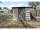 Outbuilding with grey door, metal siding, chain link fence and foliage at 206 Willow St, Lake Wales, FL 33859