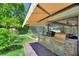 Outdoor kitchen featuring stainless steel appliances and a shaded awning for outdoor dining and entertaining at 219 Breezy Oaks Ct, Davenport, FL 33896