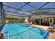 Relax by the large screened pool with sun loungers, an outdoor dining area, and clear blue water at 219 Breezy Oaks Ct, Davenport, FL 33896