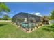 The screened-in pool provides a private and refreshing escape surrounded by lush greenery and potted plants at 219 Breezy Oaks Ct, Davenport, FL 33896
