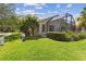 Well-maintained backyard with lush green grass, manicured shrubs, and an enclosed lanai at 223 Bell Tower W Xing, Poinciana, FL 34759