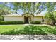 Well-manicured lawn complements the neutral exterior of this home, framed by lush greenery at 223 Bell Tower W Xing, Poinciana, FL 34759