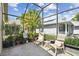Enclosed lanai with outdoor seating, potted plants, and views of the surrounding yard at 223 Bell Tower W Xing, Poinciana, FL 34759
