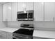 Stainless steel microwave and electric range atop quartz countertops and white cabinets at 250 Beckenham Dr, Kissimmee, FL 34758