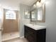 Bathroom featuring a tiled stand-up shower with window, mirror, and dark-wood cabinets at 2725 N Poinciana Blvd # 147, Kissimmee, FL 34746
