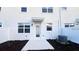 Back exterior view of a bright white modern home with a concrete patio and small garden space at 312 Nine Iron Dr, Davenport, FL 33896
