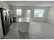 Bright kitchen features stainless steel appliances, white cabinets, center island, and grey tile flooring at 312 Nine Iron Dr, Davenport, FL 33896