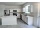 Bright kitchen features stainless steel appliances, white cabinets, center island, and grey tile flooring at 312 Nine Iron Dr, Davenport, FL 33896
