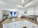 Open kitchen featuring granite countertops, white cabinetry, stainless appliances, and a view to the dining area at 340 Vail Dr, Winter Haven, FL 33884