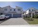 Modern townhome featuring a gray two-car garage, brick driveway, and manicured landscaping at 3470 Beau Rd, Kissimmee, FL 34746