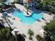 Aerial view of a community pool featuring sun deck, shade structures, and lush landscaping at 4907 Romeo Cir, Kissimmee, FL 34746