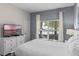 Well-lit bedroom with a queen-size bed, large window, and stylish dresser with a television at 4907 Romeo Cir, Kissimmee, FL 34746