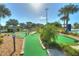 Lush mini golf course features manicured greens, mature palm trees, and a pool area with chaise lounges at 4907 Romeo Cir, Kissimmee, FL 34746