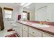 Bathroom with a double vanity, white cabinets, pink counters, and neutral tile at 5137 Links Ln, Leesburg, FL 34748