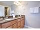 Bathroom featuring a dual sink vanity, granite countertops, and a decorative mirror at 8971 Candy Palm Rd, Kissimmee, FL 34747
