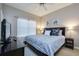 Cozy bedroom with a blue patterned comforter, ceiling fan, and a large window at 8971 Candy Palm Rd, Kissimmee, FL 34747