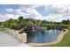 Community pond featuring a waterfall, lush landscaping, and views of the surrounding tropical foliage and blue skies at 8971 Candy Palm Rd, Kissimmee, FL 34747