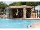 Community swimming pool with a unique rock grotto featuring a waterfall and separate water features, and lush landscaping at 8971 Candy Palm Rd, Kissimmee, FL 34747