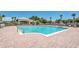 A large swimming pool on brick surface with chairs and umbrellas, surrounded by palms and lush landscaping under clear blue skies at 1999 Grand Oak Dr, Kissimmee, FL 34744