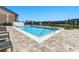 Community pool with lounge chairs near building with small patios overlooking a water feature on a beautiful sunny day at 1999 Grand Oak Dr, Kissimmee, FL 34744