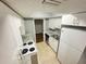 Galley kitchen featuring white cabinets, granite countertops, and white appliances at 4745 S Texas Ave # A, Orlando, FL 32839