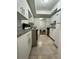 Galley kitchen with white cabinets, neutral counters, and tiled floors, leading into another room at 4745 S Texas Ave # A, Orlando, FL 32839