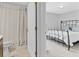 View into bathroom and bedroom; bedroom has black metal frame bed and the bathroom has a ruffled shower curtain at 1083 Snively Cir, Lake Hamilton, FL 33851