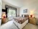 Bright bedroom features a comfortable bed, two nightstands with lamps, and a window with a view at 1301 Rebecca Dr, Haines City, FL 33844