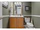 A stylish half bathroom featuring a wood vanity, white countertops, and dark green walls with decorative accents at 133 Torino Ln, Kissimmee, FL 34759