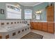 Relaxing bathroom featuring a soaking tub with tiled accents, dual vanities, and a chandelier at 133 Torino Ln, Kissimmee, FL 34759
