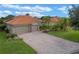 Beautiful house with a brick driveway, two-car garage, terra cotta roof, and lush landscaping with mature palms at 133 Torino Ln, Kissimmee, FL 34759