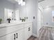 Bright and airy bathroom with double sink vanity, white cabinets, black fixtures, and wood-look flooring at 145 Willow Dr, Poinciana, FL 34759