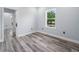 Bright bedroom featuring wood-look floors, a window with a view of a leafy tree, and neutral walls at 145 Willow Dr, Poinciana, FL 34759